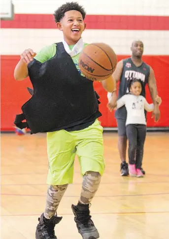  ?? PHOTOS: WAYNE CUDDINGTON ?? Chris, above, is all smiles as he competes in a skills contest while wearing a bulletproo­f vest. Ottawa police officers volunteer their time to play basketball with teens attending the after-school program run by Christie Lake Kids at the Dempsey...