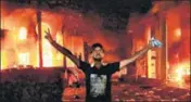  ?? AFP ?? Basra burns: An Iraqi protester flashes the victory gesture outside the burning headquarte­rs of the Iranian consulate.