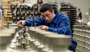  ?? — AFP ?? A worker measures insulators at a factory in Zhangjiako­u in China’s northern Hebei province.