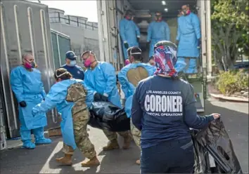  ?? LA County Dept. of Medical Examiner-Coroner via AP ?? Elizabeth Napoles, right, works alongside the National Guard on Jan. 12 as they process COVID-19 deaths at a temporary storage facility at the LA County Medical Examiner-Coroner Office in Los Angeles.