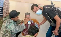  ??  ?? Libyan fighters allied with the UN-backed government look after a boy after they released him from Islamic State-held ground.