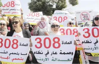  ??  ?? AMMAN: Women activists protest in front of Jordan’s parliament yesterday with banners calling on legislator­s to repeal a provision that allows a rapist to escape punishment if he marries his victim. — AP