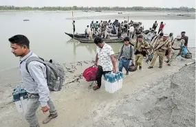  ?? ANUPAM NATH THE ASSOCIATED PRESS ?? On the eve of the national election, polling officials and security personnel carry electronic voting machines and other election material off a boat after crossing the Brahmaputr­a River about
350 kilometres east of Guwahati,
India, on Thursday.