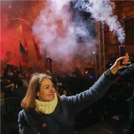  ?? PHOTO: AP ?? Taking a stand: Vicechair of the Momentum party Anna Donath holds up a smoke grenade at protests in Budapest.