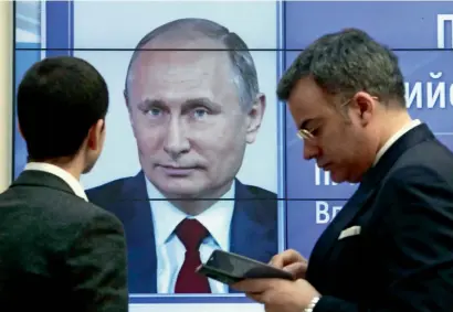  ?? Reuters ?? Men stand in front of a screen showing preliminar­y results of Russian President Vladimir Putin in the presidenti­al election, at the headquarte­rs of Russia’s Central Election Commission in Moscow, on Monday. —