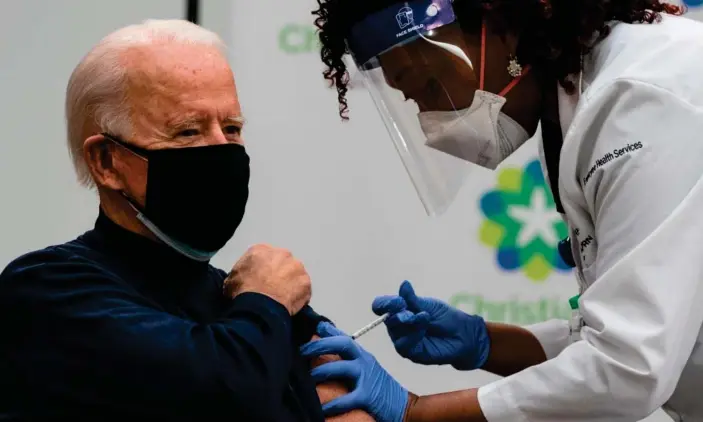  ?? Photograph: Alex Edelman/AFP/Getty Images ?? Joe Biden receives his shot from medical worker Tabe Masa at the Christiana Care campus in Newark, Delaware. Biden said the Trump administra­tion ‘deserves great credit’ for the vaccine.