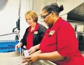  ??  ?? Rev. Deborah Ingraham, executive director of Skyline Urban Ministries, and the organizati­on’s kitchen manager Arnetta Gresham, wash a few dishes in Skyline’s newly remodeled kitchen after a Blessing of the Kitchen event on Feb. 11 at 500 SE 15.