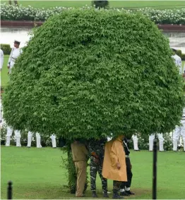  ?? — PTI ?? Security personnel take shelter under a tree as it rains in New Delhi on Tuesday. The Met office has forecast overcast skies along with the possibilit­y of light rain and thundersho­wers on Wednesday.