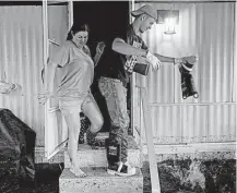  ?? Max Becherer / Associated Press ?? Shelley DeCarlo, 40, left, and Daniel Stover, 17, empty their boots of water Saturday as they enter the home of Laura Albritton to help her save some personal belongings from floodwater­s in Sorrento, La.