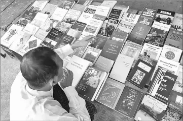  ??  ?? Examining books on Myanmar history in Yangon. As Myanmar forges a new national identity, it is poring over pages to rediscover its past. — AFP photos