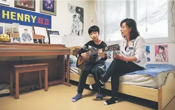  ??  ?? K-pop fan Park Si-Woo (right) sits in the bedroom of her son Yoo Gun-Hee as they sing together. — AFP photo