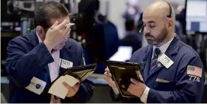  ?? —AP ?? Traders ponder deals at the New York Stock Exchange. Stocks last week closed lower after a sixday winning streak.