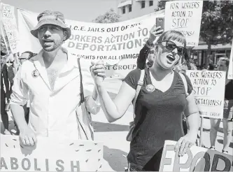  ?? JULIUS MOTAL THE ASSOCIATED PRESS ?? Thomas Muccioli and Allie Horton hold hands as they chant at the end of a march Sunday in the Queens borough of New York in opposition to the Trump administra­tion’s plan to continue raids.