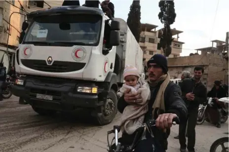  ?? AMER ALMOHIBANY/AFP/GETTY IMAGES ?? A Red Crescent convoy carrying humanitari­an aid arrives in Kfar Batna, in the rebel-held Eastern Ghouta area. A landmark truce is to take effect Saturday.