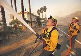  ?? Al Seib Los Angeles Times ?? VENTURA COUNTY firefighte­r Andrew Rodriguez aims water at burning trees Thursday in Faria Beach, where the blaze threatened homes near the 101 Freeway.