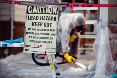  ?? Photo for The Washington Post by Timothy C. Wright ?? A worker vacuums lead-contaminat­ed paint chips that had been scraped from an exterior wall of a home in Richmond, Virginia.