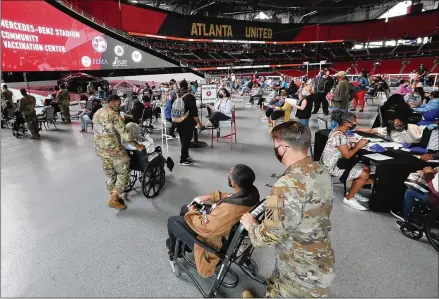  ?? PHOTOS BY CURTIS COMPTON/CURTIS.COMPTON@AJC.COM ?? U.S. Army soldiers from Fort Stewart help some seniors through the process of getting their first vaccinatio­n Wednesday at Atlanta’s Mercedes-benz Stadium, the state’s largest Community Vaccinatio­n Center.