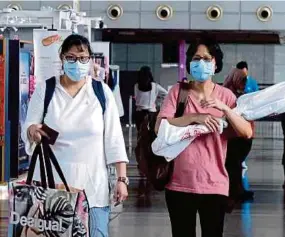  ??  ?? People wearing face masks at the Bangunan Sultan Iskandar Customs, Immigratio­n and Quarantine Complex in Johor Baru yesterday.