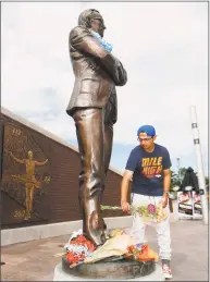  ?? David Zalubowski / Associated Press ?? Lifelong Broncos fan Adam Busack of Littleton, Colo., places a bouquet of flowers at a statue of Broncos owner Pat Bowlen outside Mile High Stadium on Friday. Bowlen died Thursday night.
