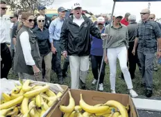  ?? EVAN VUCCI/THE ASSOCIATED PRESS ?? U.S. President Donald Trump, centre, and first lady Melania Trump, in white pants, arrive to hand out food to people impacted by hurricane Irma at Naples Estates on Thursday, in Naples, Fla.