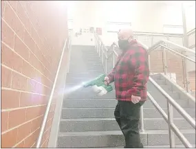  ?? COURTESY PHOTO ?? Jon Purifoy, principal of Farmington High School, uses an electrosta­tic fog machine to disinfect high-touch areas on the stairway leading to the second floor of the high school building. Farmington School District last week reinstated its mask mandate because of a higher rate of covid-19 cases and increased its daily disinfecti­ng measures.