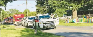  ??  ?? A Gravette Police officer gets back in his vehicle after walking across to deliver a birthday gift to Taylor Crose during his 16th birthday parade. Behind him are several police and fire vehicles which participat­ed in the parade.