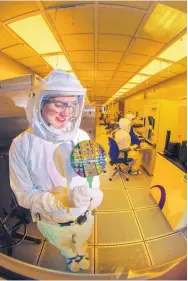  ?? COURTESY OF RANDY MONTOYA/SANDIA LABS ?? A microelect­ronics technician at Sandia National Laboratori­es studies a wafer, a thin slice of semiconduc­tor material used in integrated circuits.