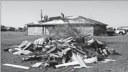  ?? WILLIAM WIDMER/THE NEW YORK TIMES ?? Austin Pearce, center, works with his uncles to replace a tarp over the weekend in Iowa, Louisiana. The tarp was initially installed on his roof after Hurricane Laura hit Aug. 27.