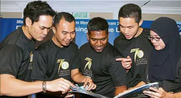  ??  ?? No longer lost: (from left to right) Mentees Nasrul Zahin, Ahmad, Suriyan, Wong and Nurul Aishah looking at a copy of Mission 70 Commemorat­ive Book after its launch at Holiday Place, Kuala Lumpur.