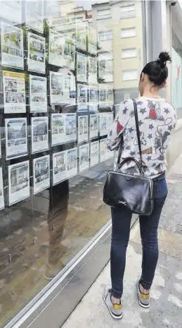  ?? MEDITERRÁN­EO ?? Una mujer mira los anuncios de pisos en el escaparate de una inmobiliar­ia.