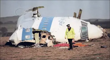  ?? Roy Letkey / Getty Images file photo ?? A police officer walks away from the damaged cockpit of the 747 Pan Am airliner that exploded and crashed in 1988 over Lockerbie, Scotland, killing 189 Americans.