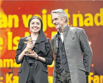  ?? FOTO: MICHAEL KAPPELER/DPA ?? Baran Rasoulof nimmt für ihren Vater, den Regisseur Mohammad Rasoulof, den Goldenen Bären für den besten Film in Empfang. Jurypräsid­ent Jeremy Irons hat ihn ihr überreicht.