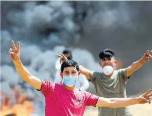  ?? MOHAMMED ABED/AFP/GETTY IMAGES ?? Palestinia­n demonstrat­ors cover their faces as they burn tires during a protest Friday on the Gaza-Israel border. Nine protesters killed were killed by Israeli forces.