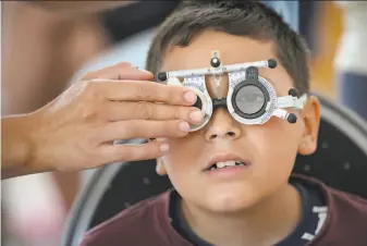  ?? Vadim Ghirda / Associated Press ?? A boy undergoes an eyesight examinatio­n performed by volunteer ophthalmol­ogists, in Nucsoara, Romania. Many rural children have never been screened by an ophthalmol­ogist.