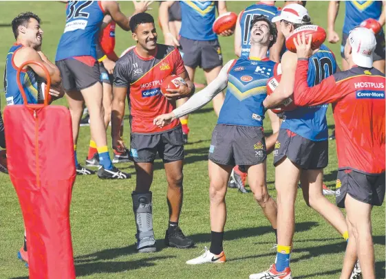  ?? Picture: AAP/DAVE HUNT ?? Touk Miller wears a moon boot as he shares a lightheart­ed moment with Alex Sexton at a Suns training session on Wednesday,