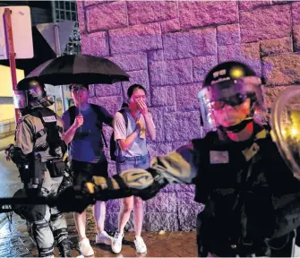  ?? REUTERS ?? A woman cries as she watches riot police detain an anti-government protester during a demonstrat­ion following the government’s ban on face masks under emergency law, at Kowloon Tong, in Hong Kong.