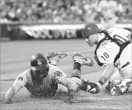  ?? Matt Slocum Associated Press ?? AUSTIN BARNES dives past Phillies catcher J.T. Realmuto to score on a trick play during the Dodgers’ six-run fourth inning Monday.