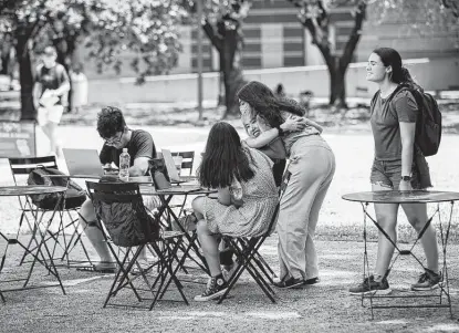  ?? Marie D. De Jesús / Staff photograph­er ?? A masked Rice University student hugs an unmasked student Monday. Masks are still required indoors at all times unless a person is in their own enclosed space, officials said. Community members and visitors are encouraged to wear masks in crowds.