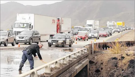  ?? Al Seib
Los Angeles Times ?? CHP SGT.
Joseph Davy works to clear a drain on southbound lanes of the 101 Freeway, where mud and debris from a recent brush fire in Solimar Beach blocked traffic.