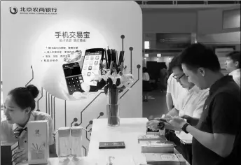  ?? PROVIDED TO CHINA DAILY ?? A staff member of Beijing Rural Commercial Bank introduces the company’s mobile app to a client at the 2nd China (Beijing) Internatio­nal Internet Era Exposition.