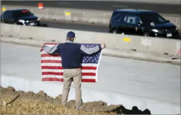  ?? DAVID ZALUBOWSKI — THE ASSOCIATED PRESS ?? David Morgan of Highlands Ranch, Colo., holds an American flag as a procession of law enforcemen­t vehicles accompany a hearse carrying the body of a sheriff’s deputy shot and killed while responding to a domestic disturbanc­e Sunday, Dec. 3, in...