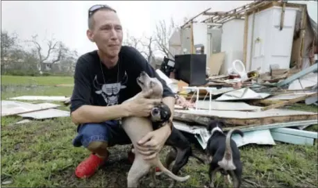  ?? ERIC GAY — THE ASSOCIATED PRESS ?? Sam Speights tries to hold back tears while holding his dogs and surveying the damage to his home in the wake of Hurricane Harvey, Sunday in Rockport, Texas. Speights tried to stay in his home during the storm but had to move to other shelter after he...