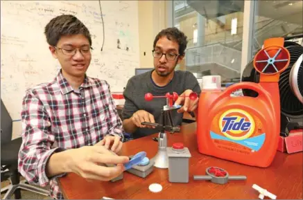  ?? GREG GILBERT, SEATTLE TIMES ?? Justin Chan, left, and Vikram Iyer show plastic devices they 3D printed that have no batteries, but can communicat­e over a Wi-Fi network.