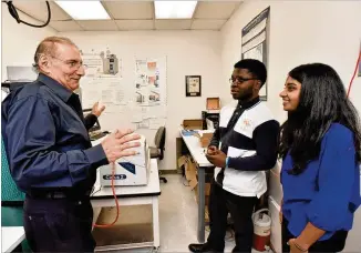  ?? HYOSUB SHIN PHOTOS / HSHIN@AJC.COM ?? Dr. Simon Yunes (left), Senior Applicatio­n Scientist at Micromerit­ics, talks to former student interns Patrick Aghadiuno and Elizabeth Karivelil (right), both GSMST students, in the lab where they made the breakthrou­ghs at Micromerit­ics Instrument...