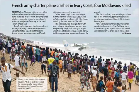  ?? — AFP ?? People stand on the beach of PortBouet in Abidjan as they look at the wreckage of a cargo plane that crashed off Ivory Coast on Saturday.