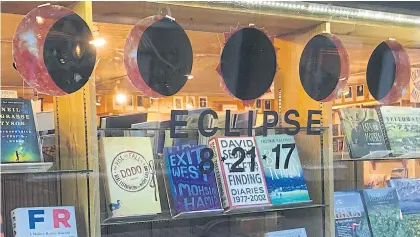  ??  ?? LEFT Books and a cardboard cutout representa­tion of the moon eclipsing the sun are seen at a bookstore in Jackson, Wyoming.