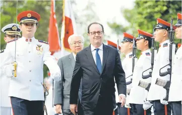  ?? — Reuters photo ?? Hollande inspects an honour guard with Singaporea­n counterpar­t Tony Tan during a welcome ceremony at the Istana in Singapore.