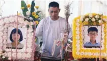  ??  ?? Swee Bok standing beside the coffins bearing the remains of his son and daughter at the funeral ceremony yesterday before the bodies were cremated in Batu Gantung.