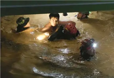  ?? CHANG W. LEE/THE NEW YORK TIMES ?? Typhoon Hinnamnor: A survivor is rescued from a flooded undergroun­d parking lot Tuesday in the southern city of Pohang, South Korea. The most powerful typhoon to hit South Korea in years killed at least six people, destroyed roads and knocked over power lines. Vehicles with smashed windows and open trunks lay scattered on roads.