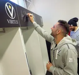  ??  ?? Firme Pietro Aradori autografa il suo posto nello spogliatoi­o della Virtus: il restyling è stato presentato ieri con Matteo Lepore e Alberto Bucci